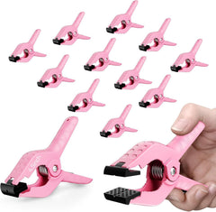Set of pink spring clamps on a white background, with a hand opening one to show its black grip pads.